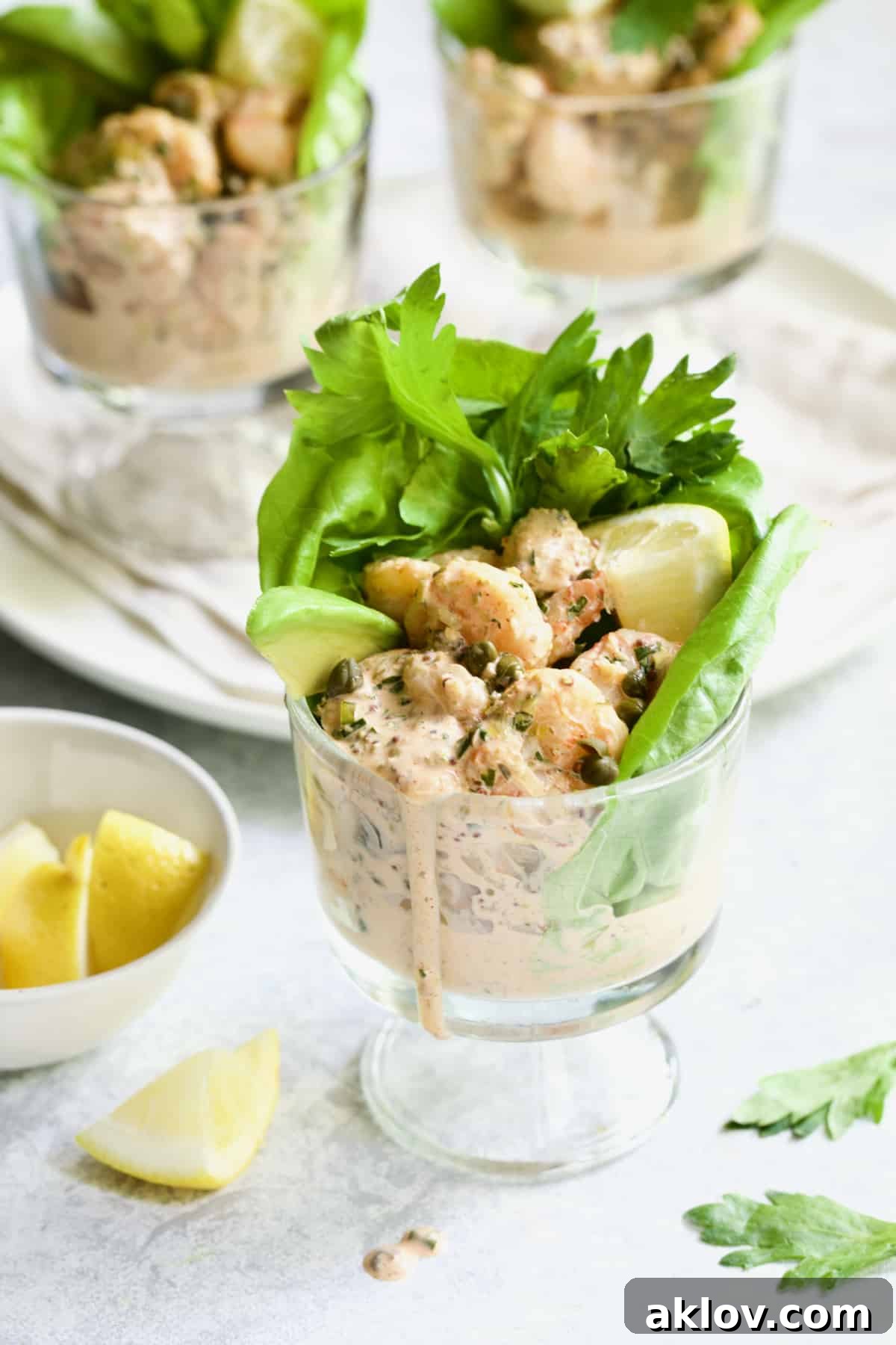 Sriracha Shrimp Remoulade Cocktail with a vibrant lemon wedge and fresh celery leaves, highlighting its colorful presentation.