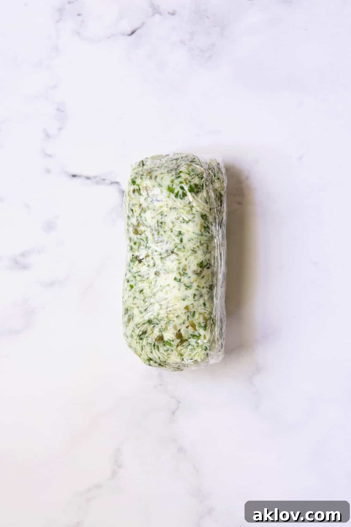 Herb - Caper Butter formed into a log wrapped in plastic wrap.