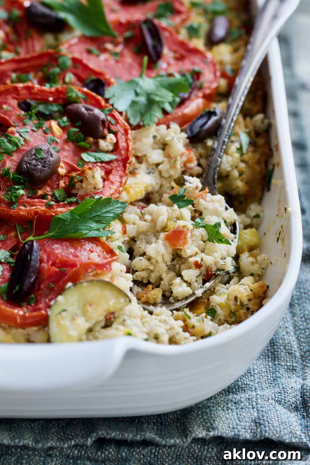 A spoonful of Greek Brown Rice and Vegetable Casserole being scooped from the baking dish, highlighting its hearty texture and generous ingredients.