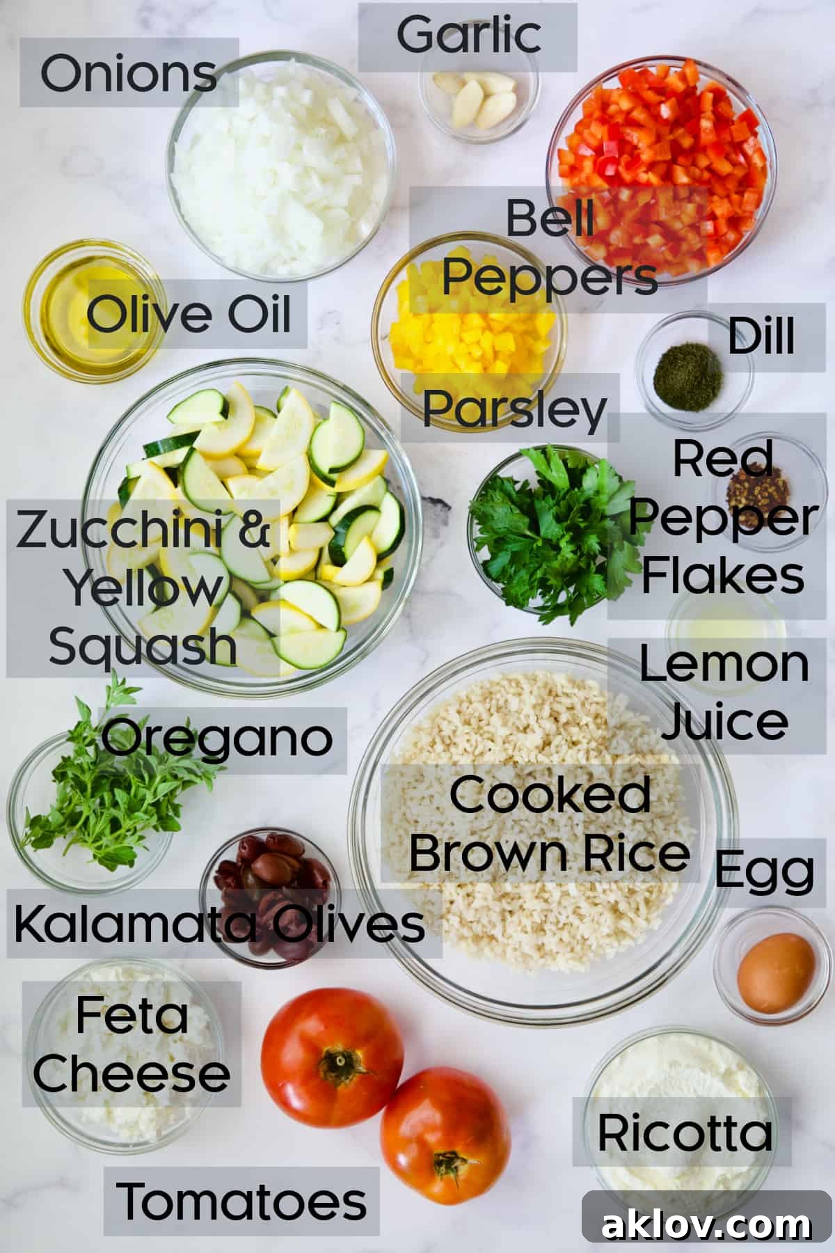 Various fresh ingredients for Greek Brown Rice and Vegetable Casserole neatly arranged in glass bowls, including chopped vegetables, herbs, and cheese.