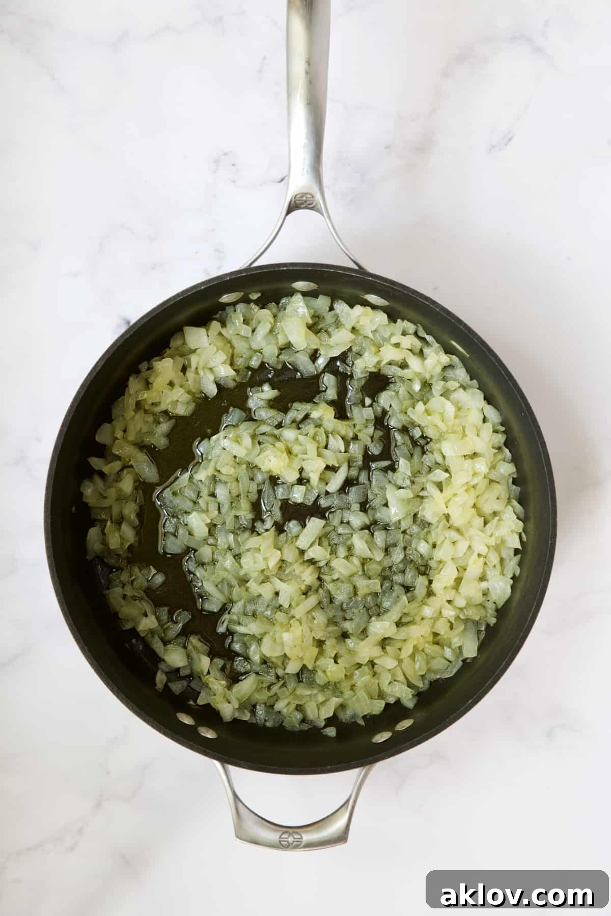 Chopped onions gently cooking in olive oil in a skillet, turning translucent and fragrant.