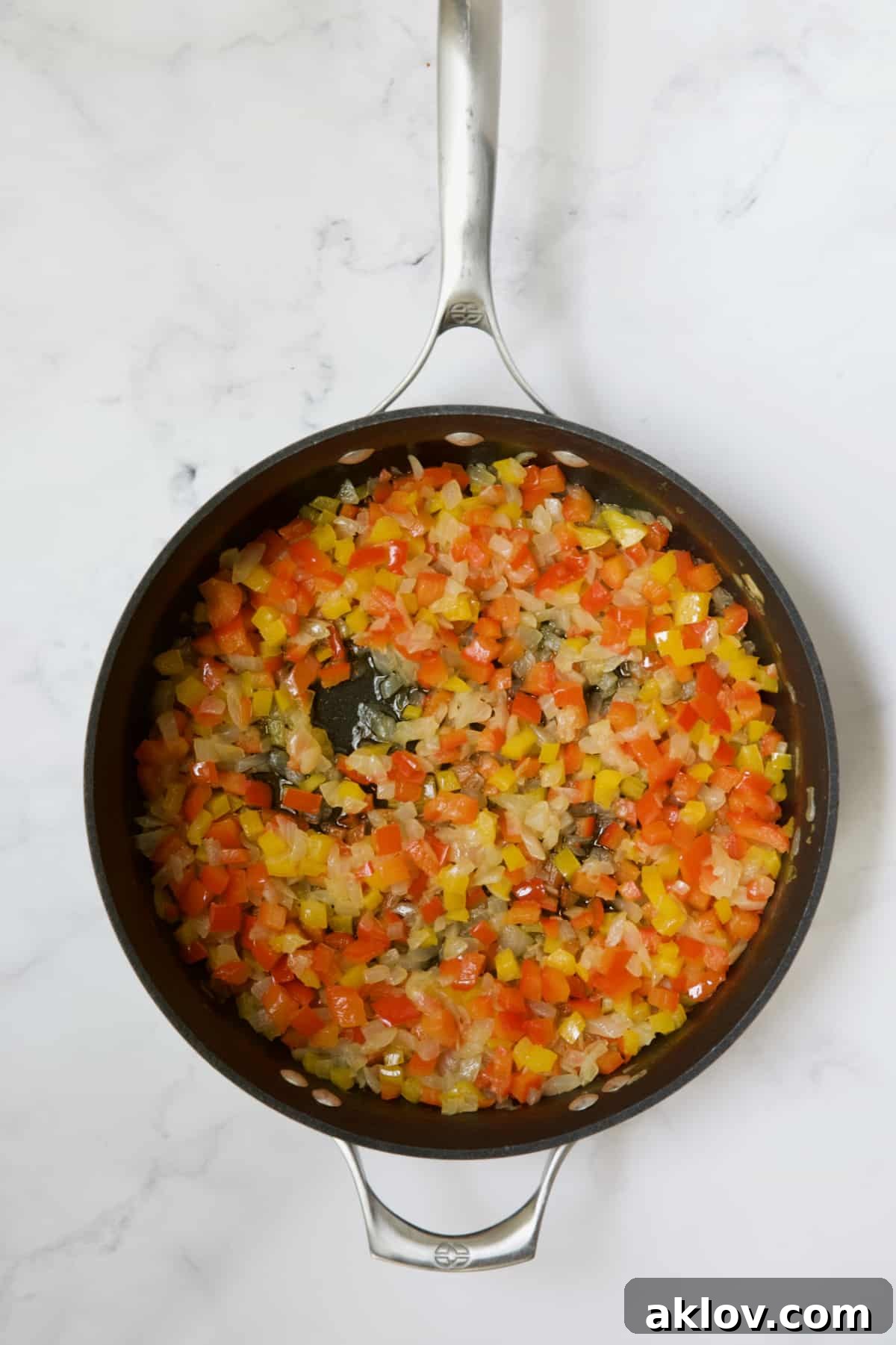 Sautéed onions and bell peppers cooking in a skillet, softened and vibrant.