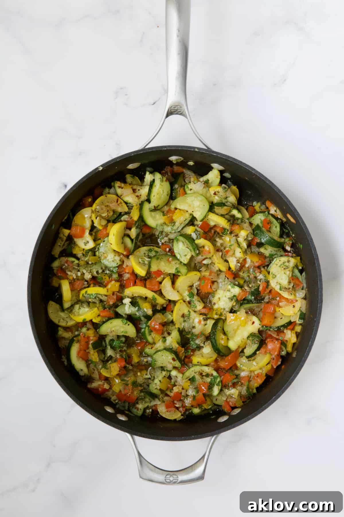 Sautéed onions, bell peppers, zucchini, and yellow squash in a skillet, showcasing their tender texture and bright colors.