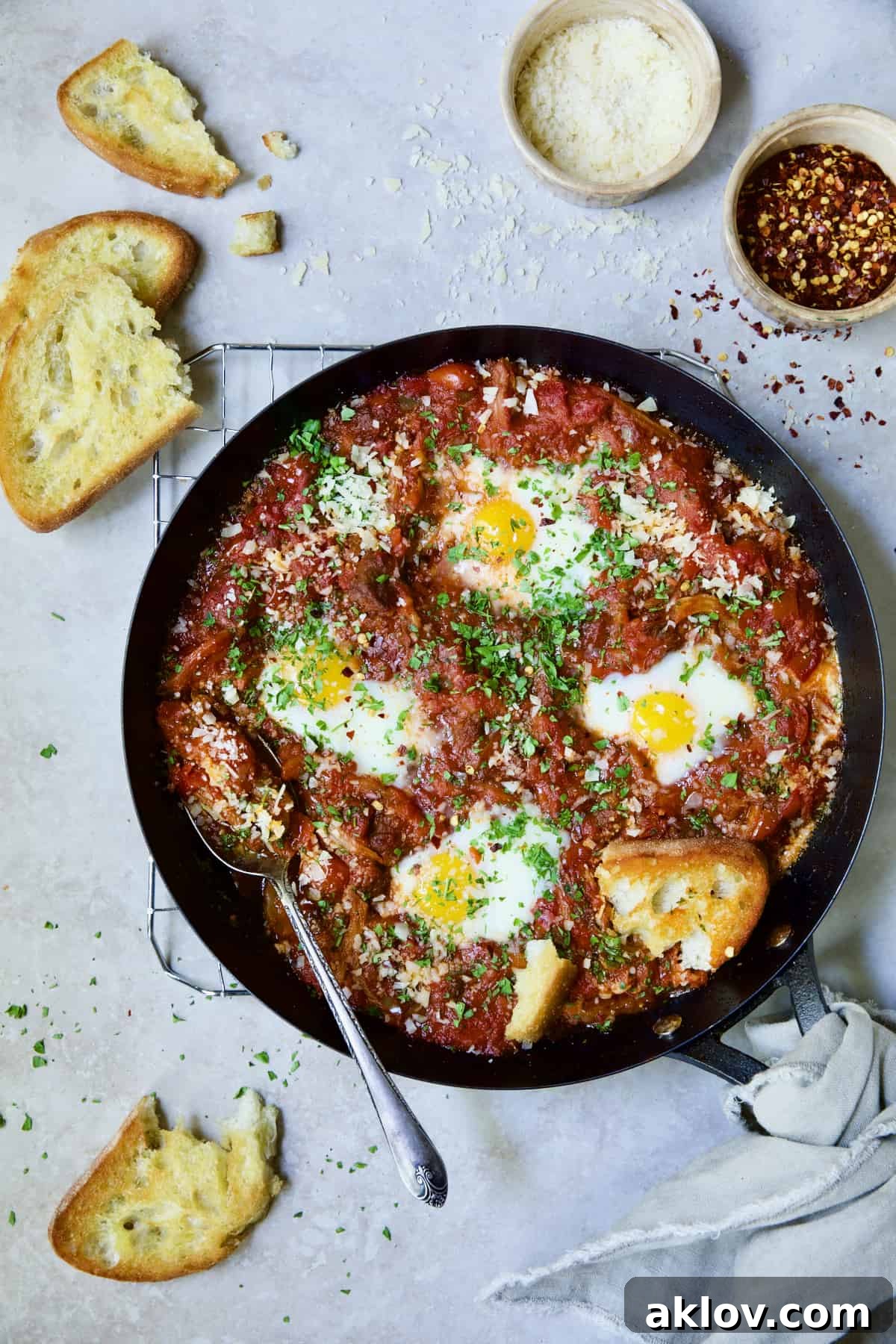 Eggs in Purgatory with Italian Sausage in skillet with broken toasted bread.