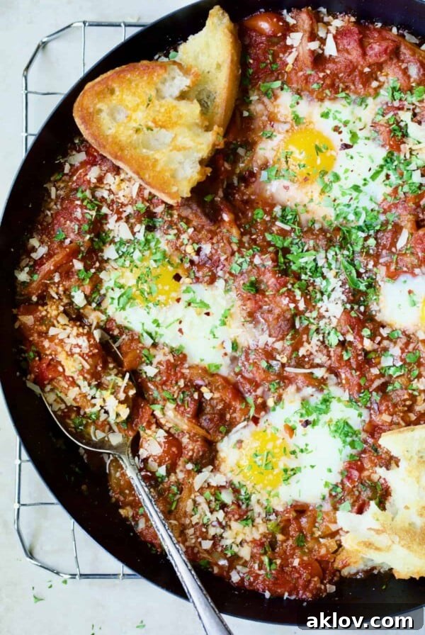 Eggs in Purgatory with Italian Sausage in skillet with toasted bread.