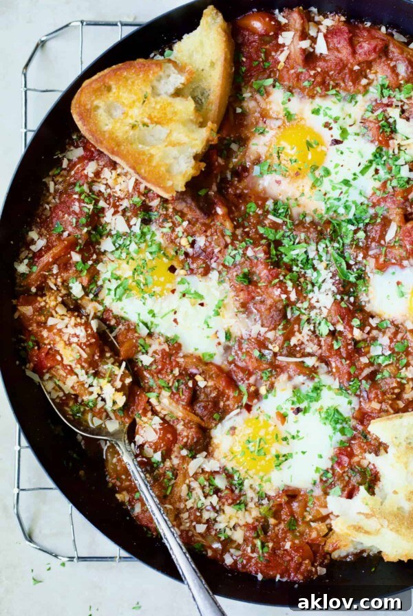 Eggs in Purgatory with Italian Sausage in skillet with toasted bread, showcasing a rich, savory dish.