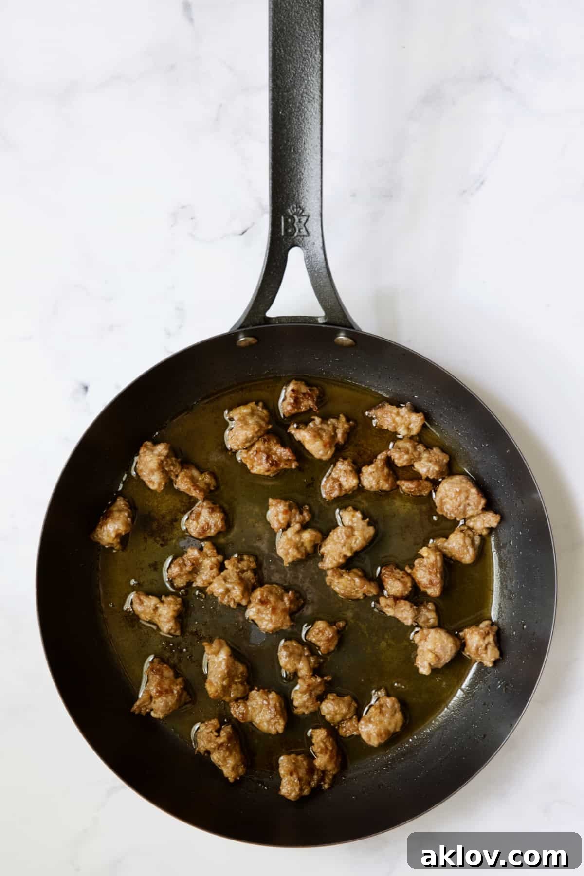 Molten Sunset Eggs 5 Crumbled and browned hot Italian sausage cooking in a black cast-iron skillet, ready to be removed.