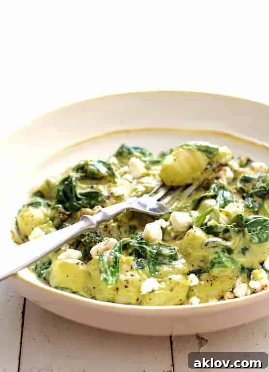 Gnocchi with Spinach and Avocado Goat Cheese Sauce in white bowl.