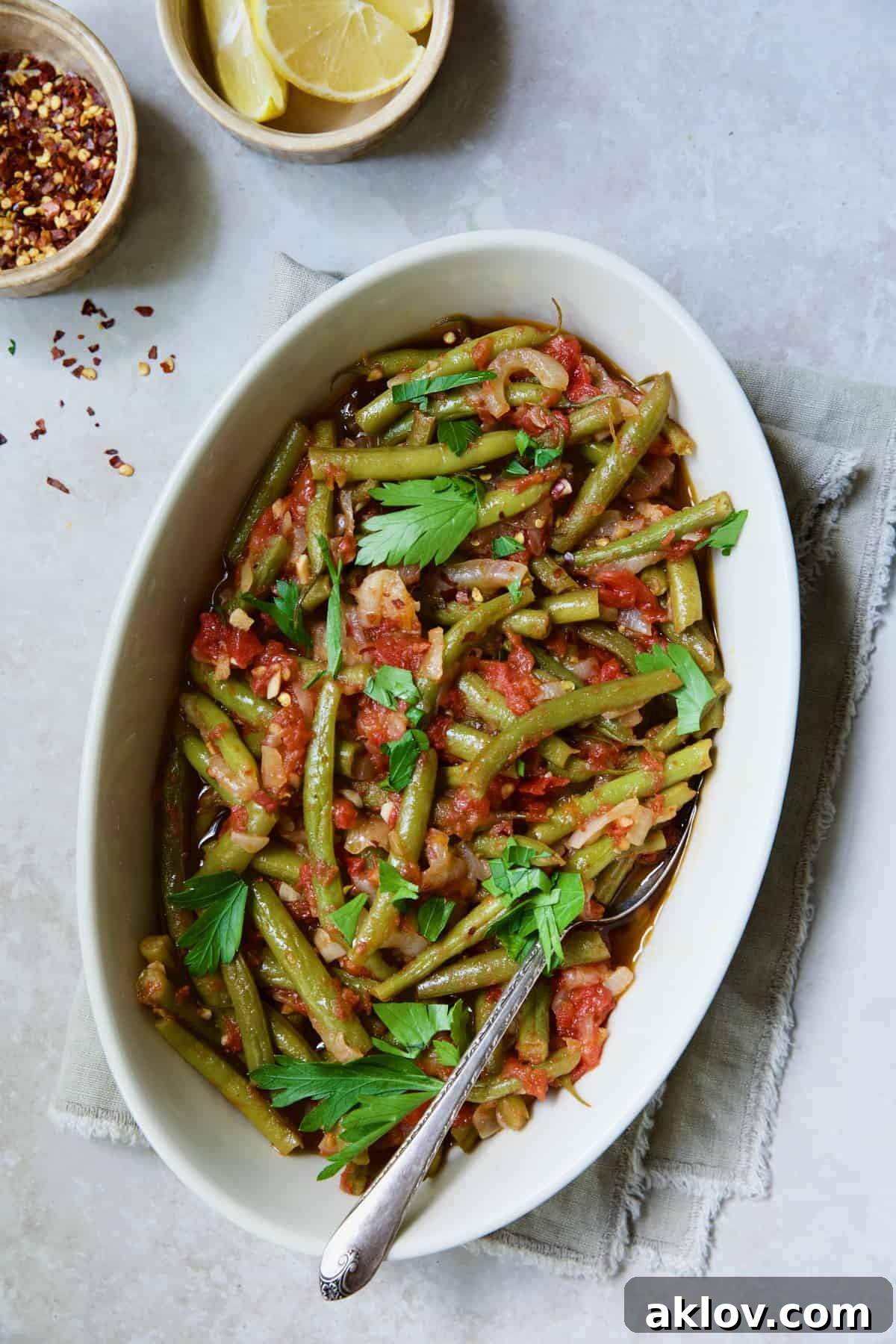 Mediterranean Green Bean and Tomato Stew 12 Mediterranean Braised Green Beans with Tomatoes in oval serving dish garnished with fresh parsley.