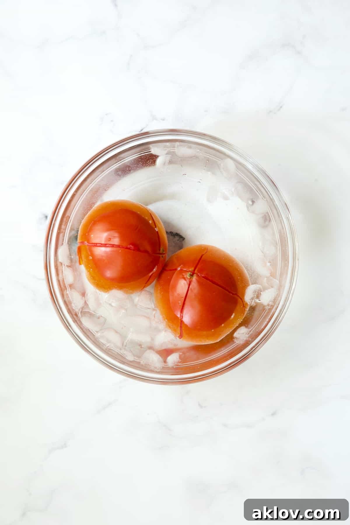 Mediterranean Green Bean and Tomato Stew 6 Two tomatoes in ice bath in glass bowl.