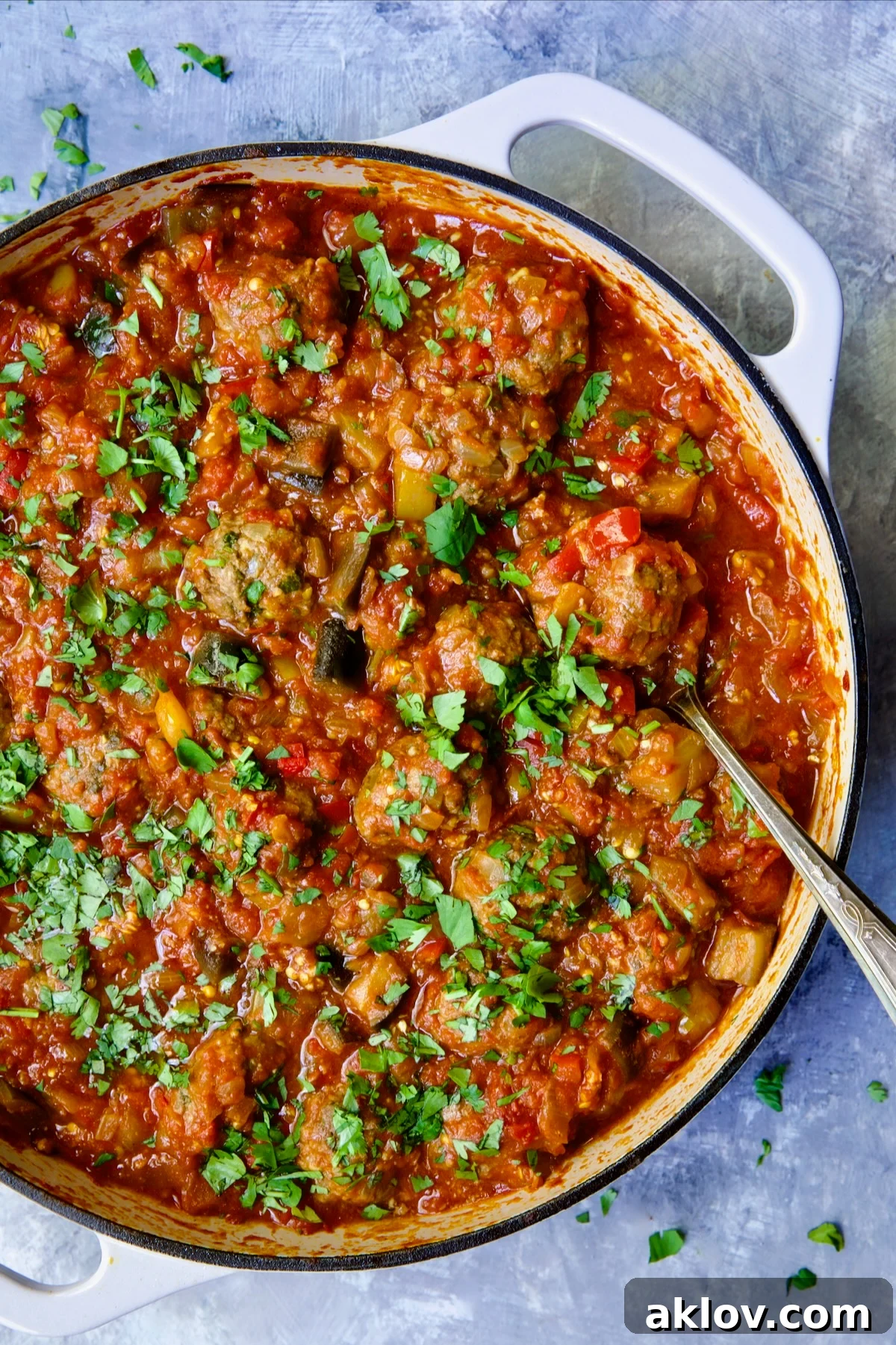 Moroccan Spiced Kofta Stew 2 Moroccan Meatball Stew in white enamel cast iron skillet with serving spoon.