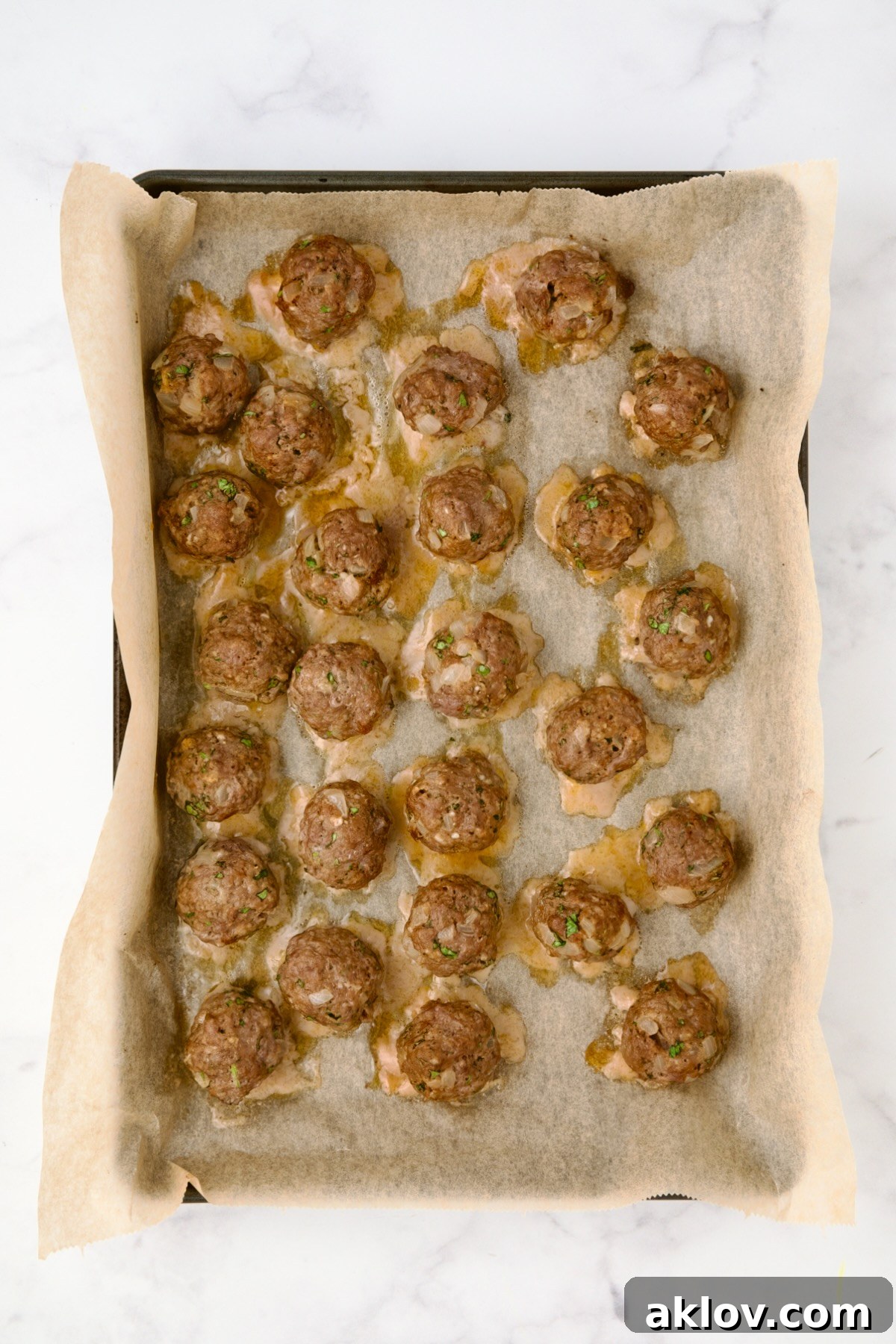 Moroccan Spiced Kofta Stew 16 26 baked meatballs on parchment paper lined rimmed baking sheet.