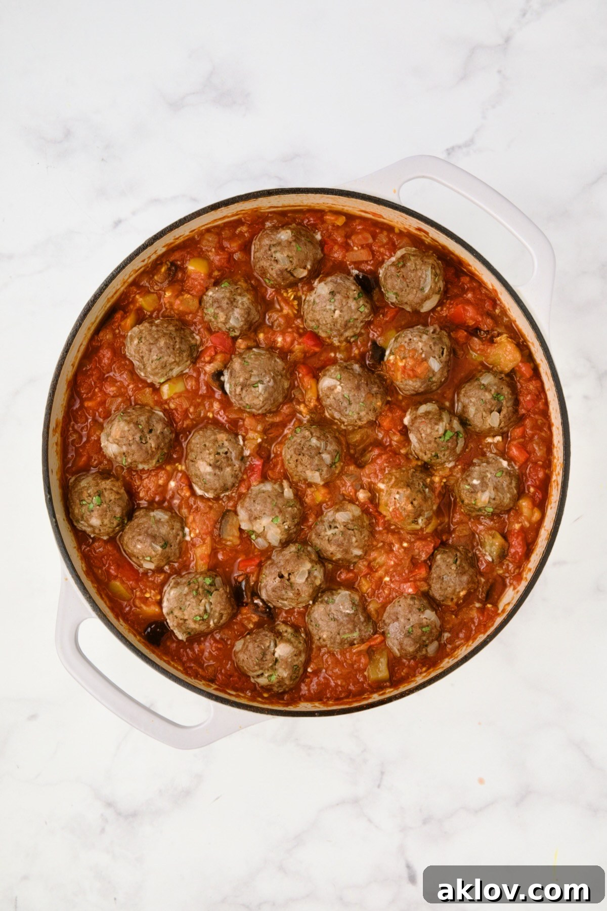 Moroccan Spiced Kofta Stew 17 Meatballs added to finished sauce in white enamel cast iron skillet.
