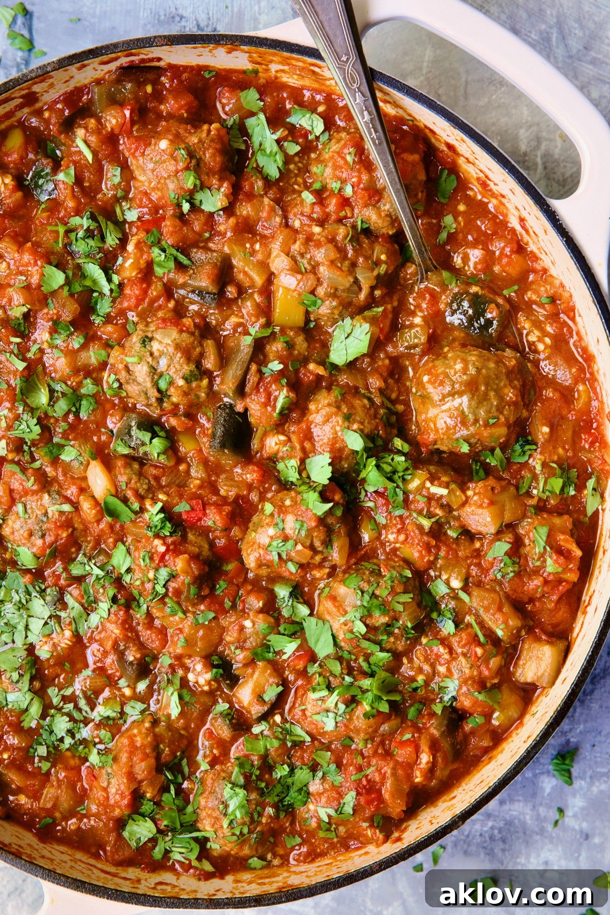 Moroccan Spiced Kofta Stew 19 Moroccan Meatball Stew in white enamel cast iron skillet with serving spoon.
