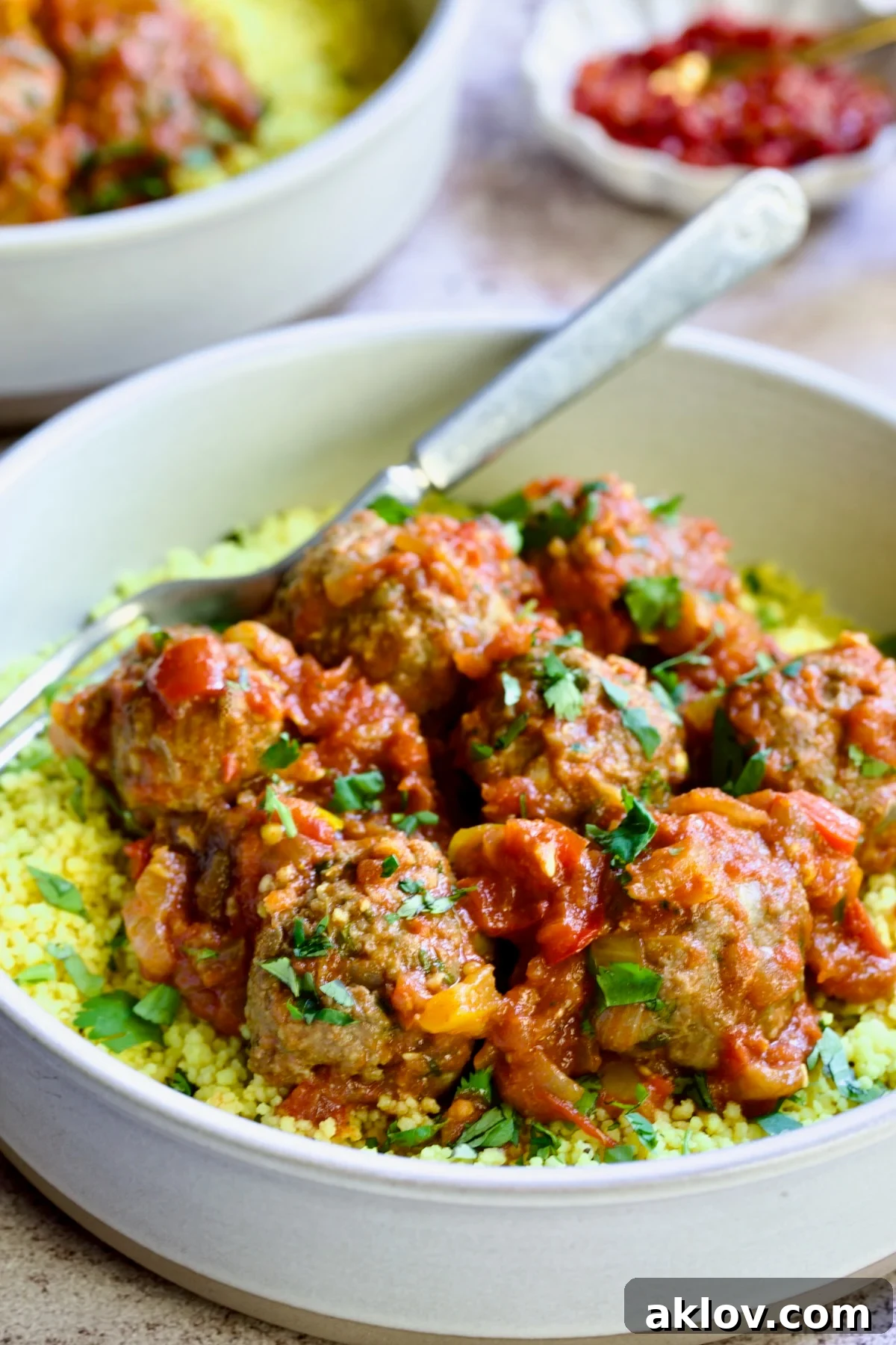 Moroccan Spiced Kofta Stew 22 One serving of Moroccan Meatball Stew in earthenware bowl over couscous.