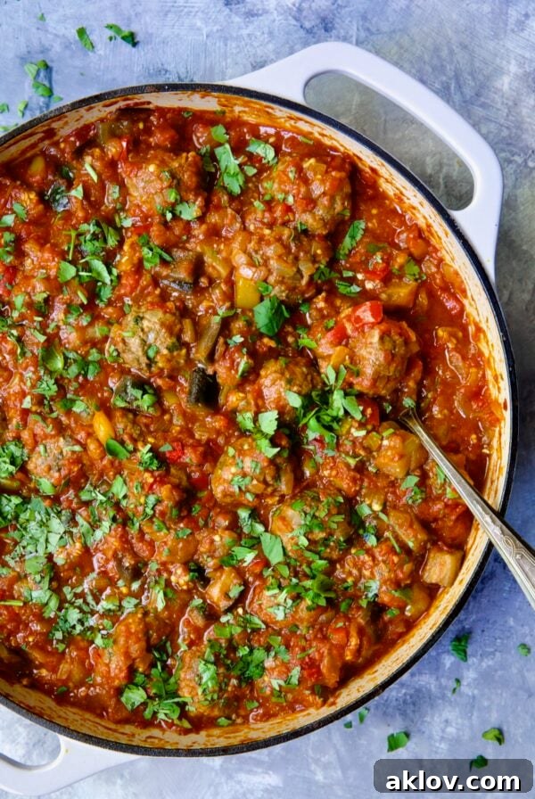 Moroccan Spiced Kofta Stew 23 Moroccan Meatball Stew in white enamel cast iron skillet with serving spoon.