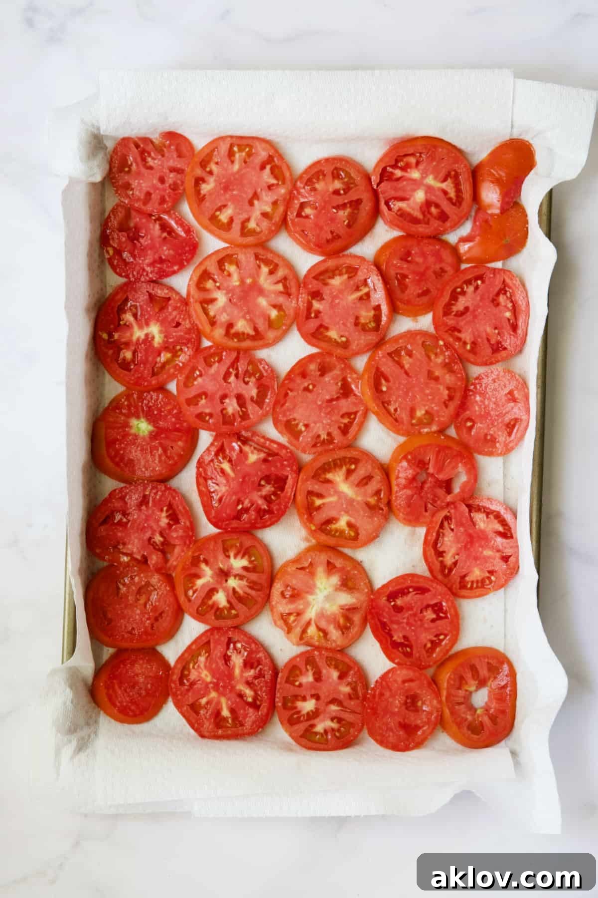 Tomato slices on paper towel-lined baking sheet.