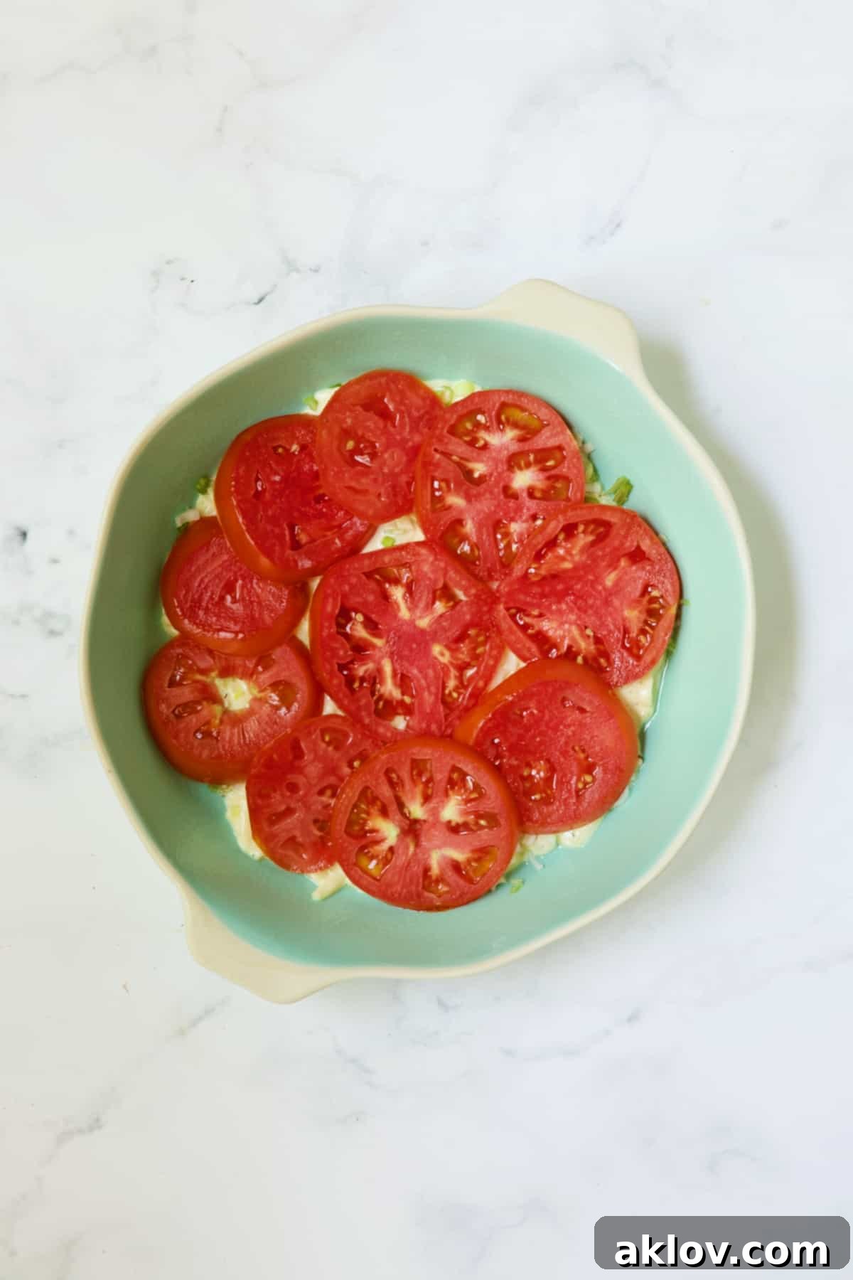 First layer of tomatoes for tomato pie in blue pie pan.