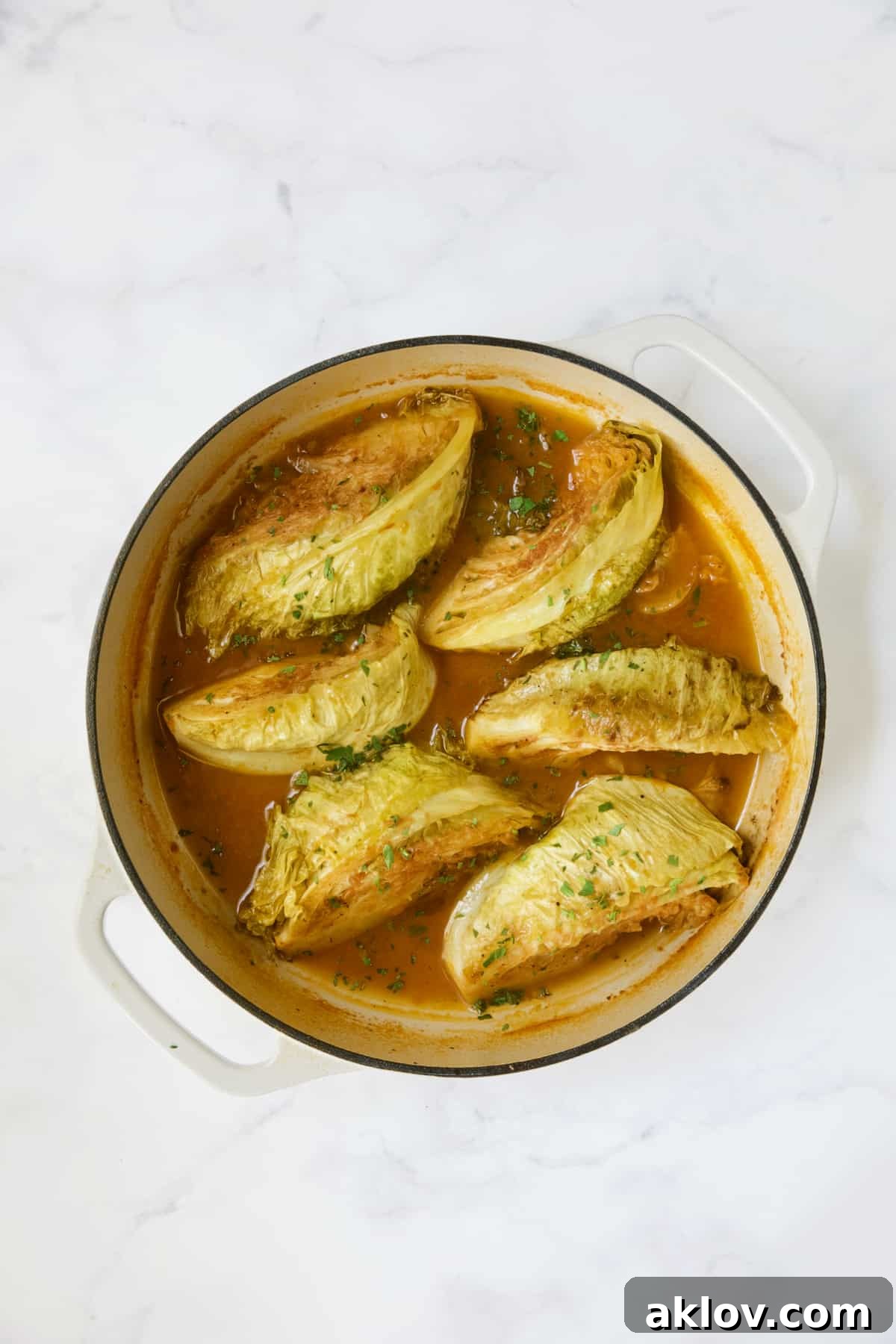 Six cabbage wedges in white enamel cast iron skillet.