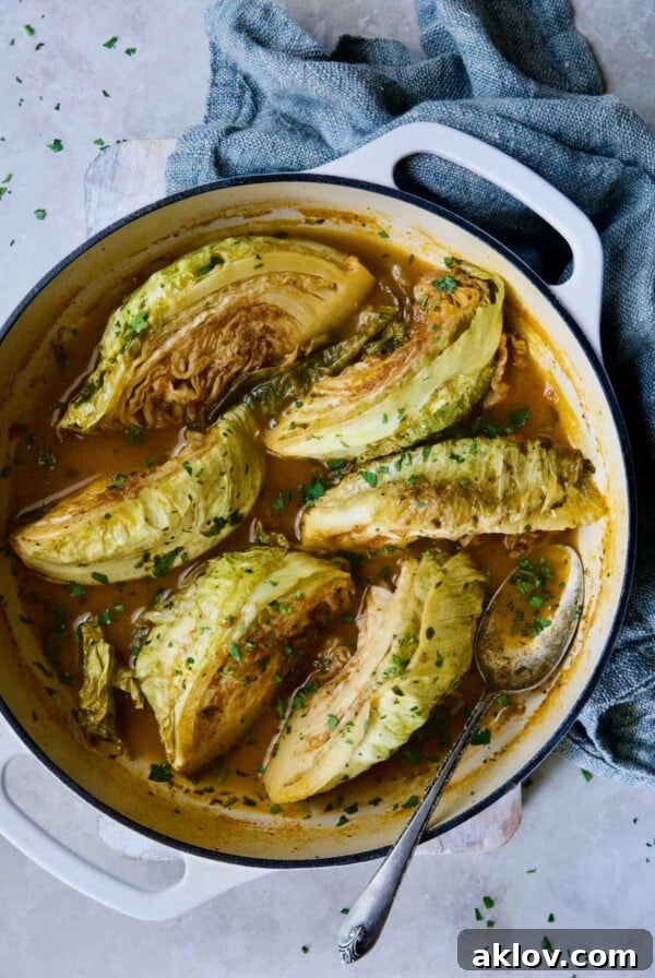 Cider Vinegar Braised Cabbage Wedges in white enamel cast iron skillet with blue napkin.