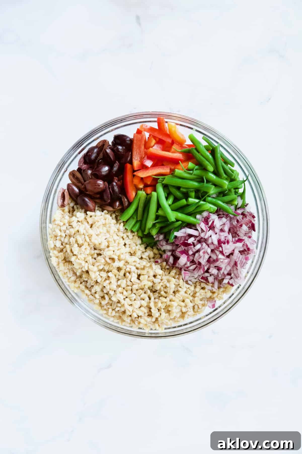 Ingredients for Mediterranean Barley Salad in glass bowl not yet stirred together.
