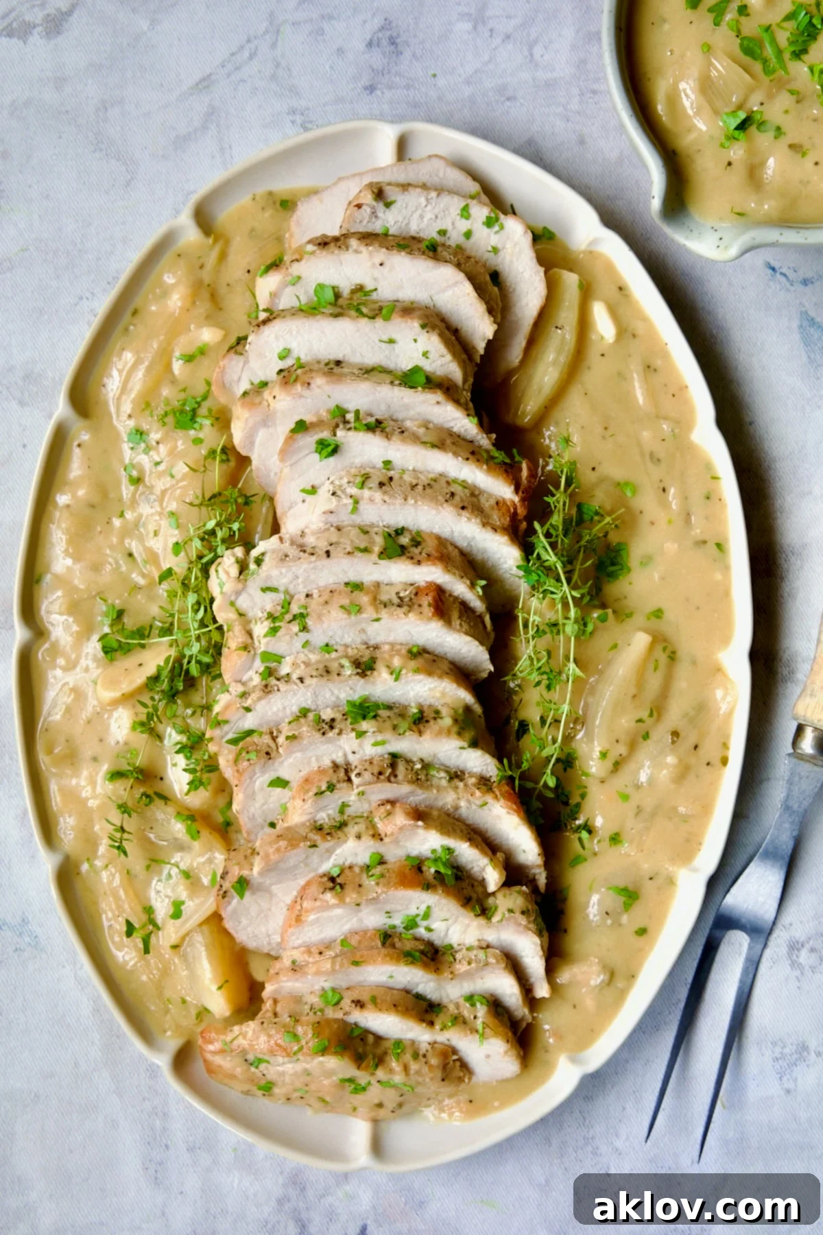 Exquisite Braised Pork Loin in Dijon Mustard Sauce, artfully arranged on a scalloped oval platter and garnished with fresh thyme sprigs, promising a gourmet experience.