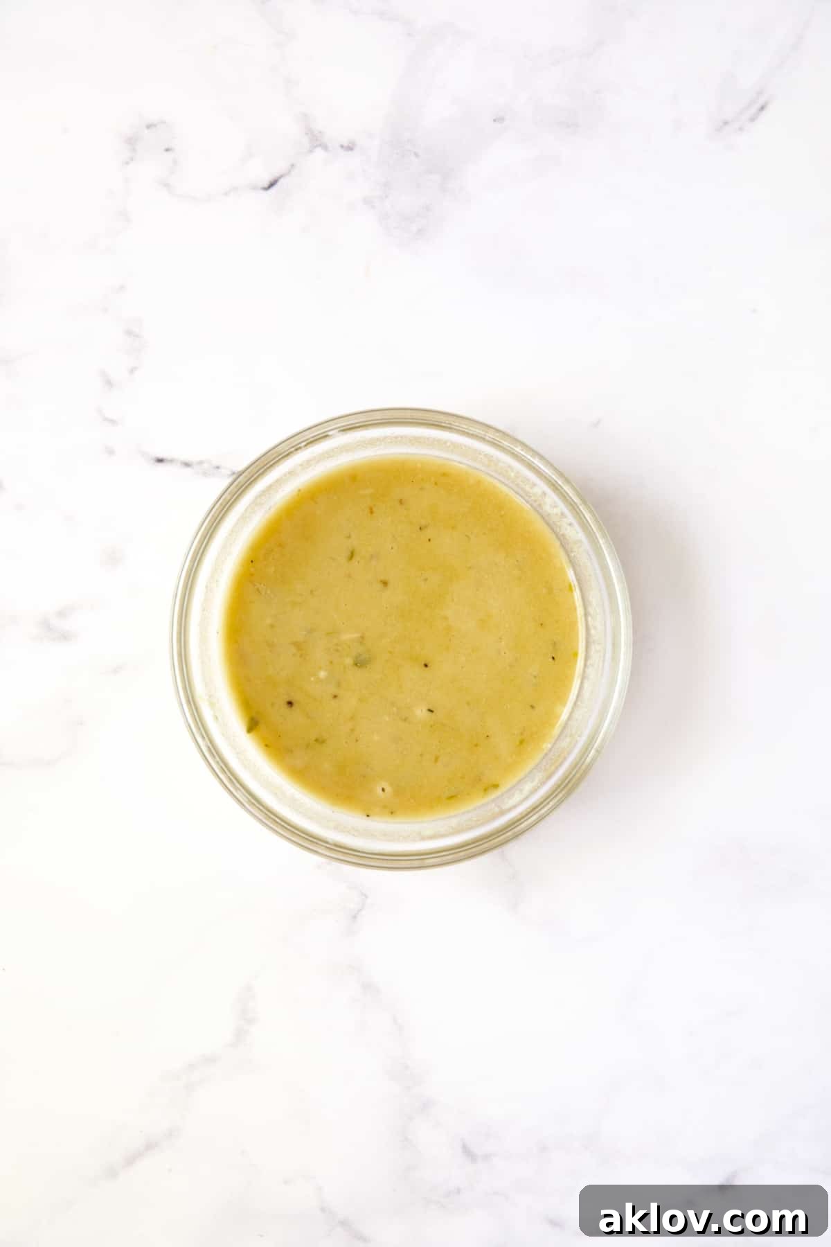 A bowl containing a smooth flour and braising liquid slurry, prepared to thicken the Dijon mustard sauce.
