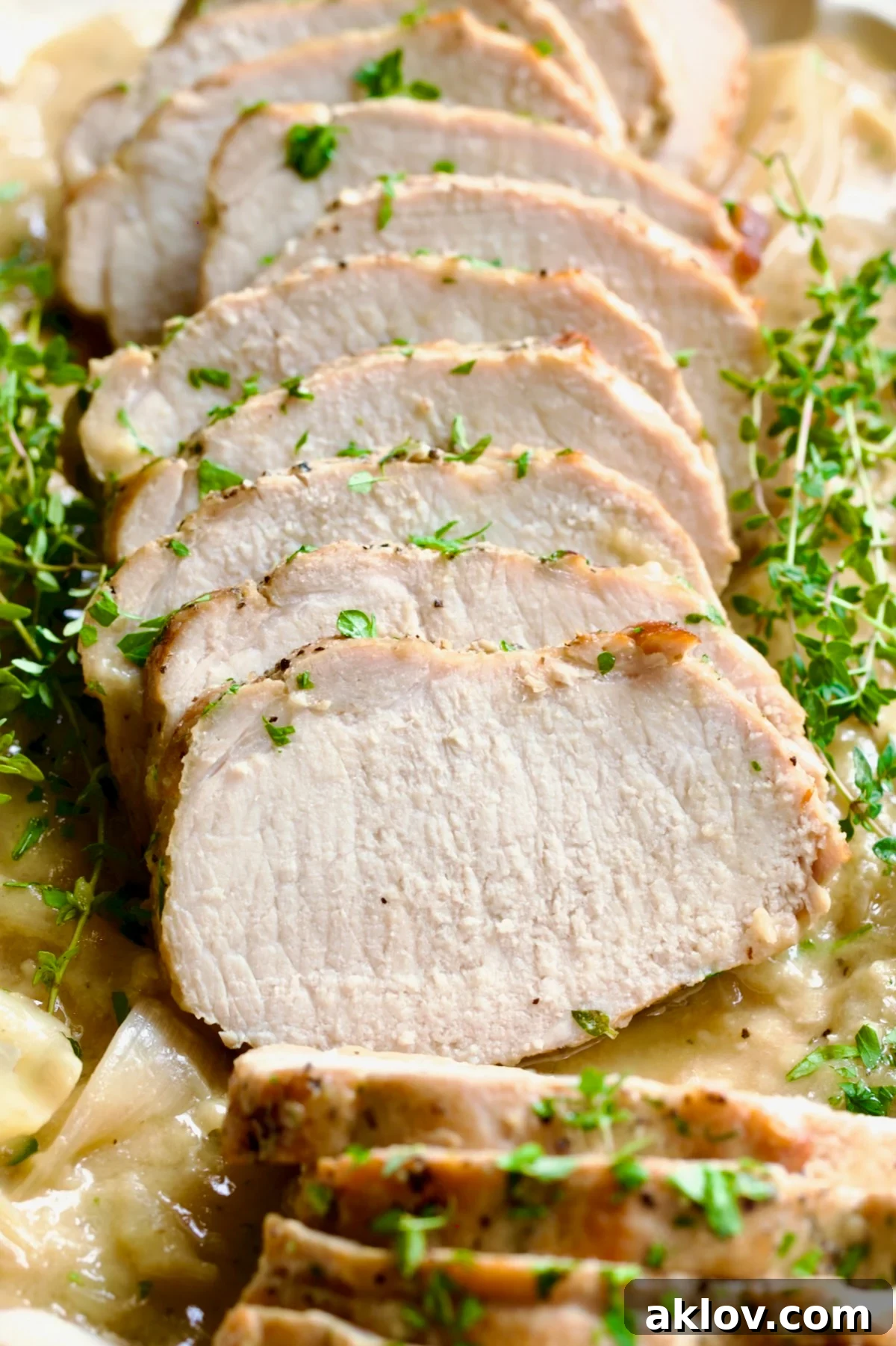 A stunning overhead shot of Braised Pork Loin in Dijon Mustard Sauce, sliced and served on a platter, garnished with fresh thyme, ready for a gathering.