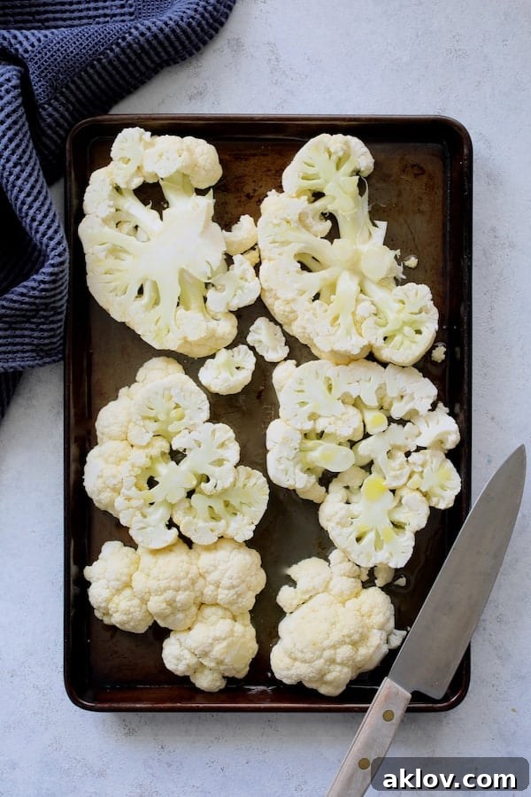 Photo of cauliflower steaks on baking sheet ready for roasting.
