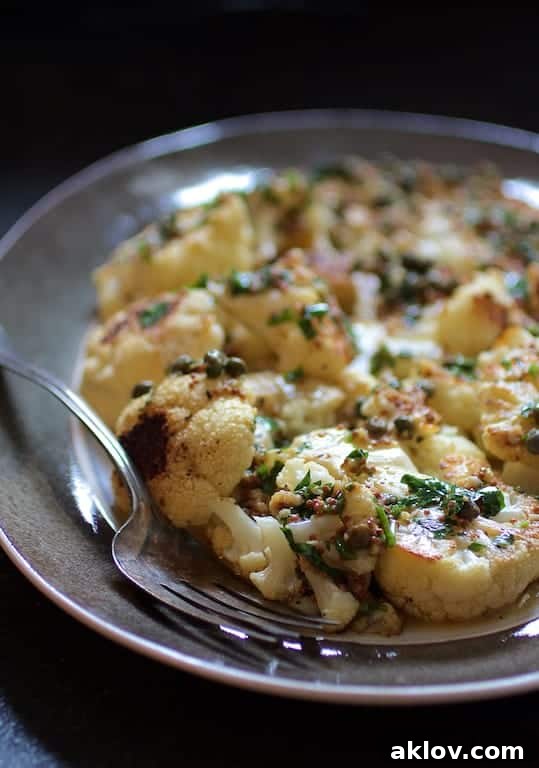 Photo of Roasted Cauliflower Steaks with Mustard Caper Brown Butter on gray-rimmed platter with serving fork.