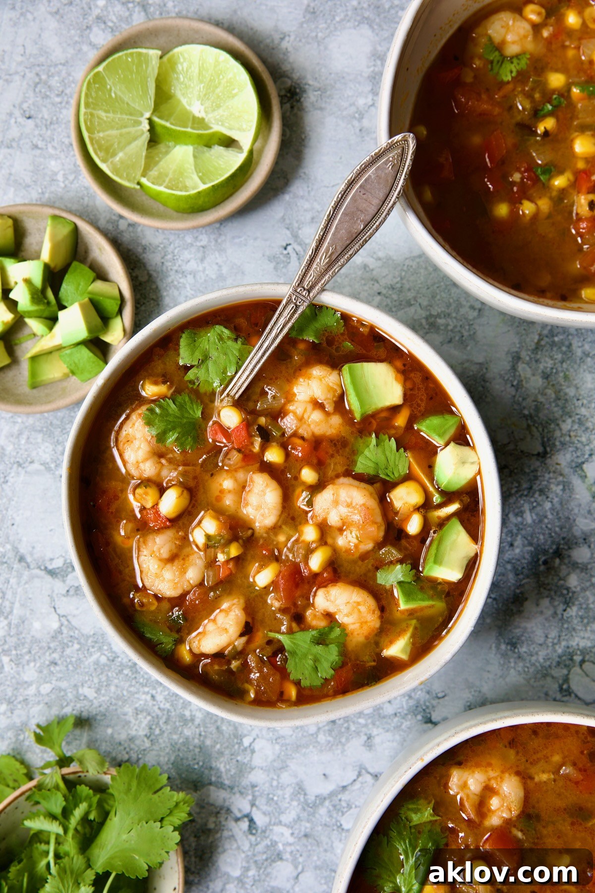 A beautifully garnished bowl of Shrimp and Corn Soup, featuring fresh cilantro and a bright lime wedge on the side.