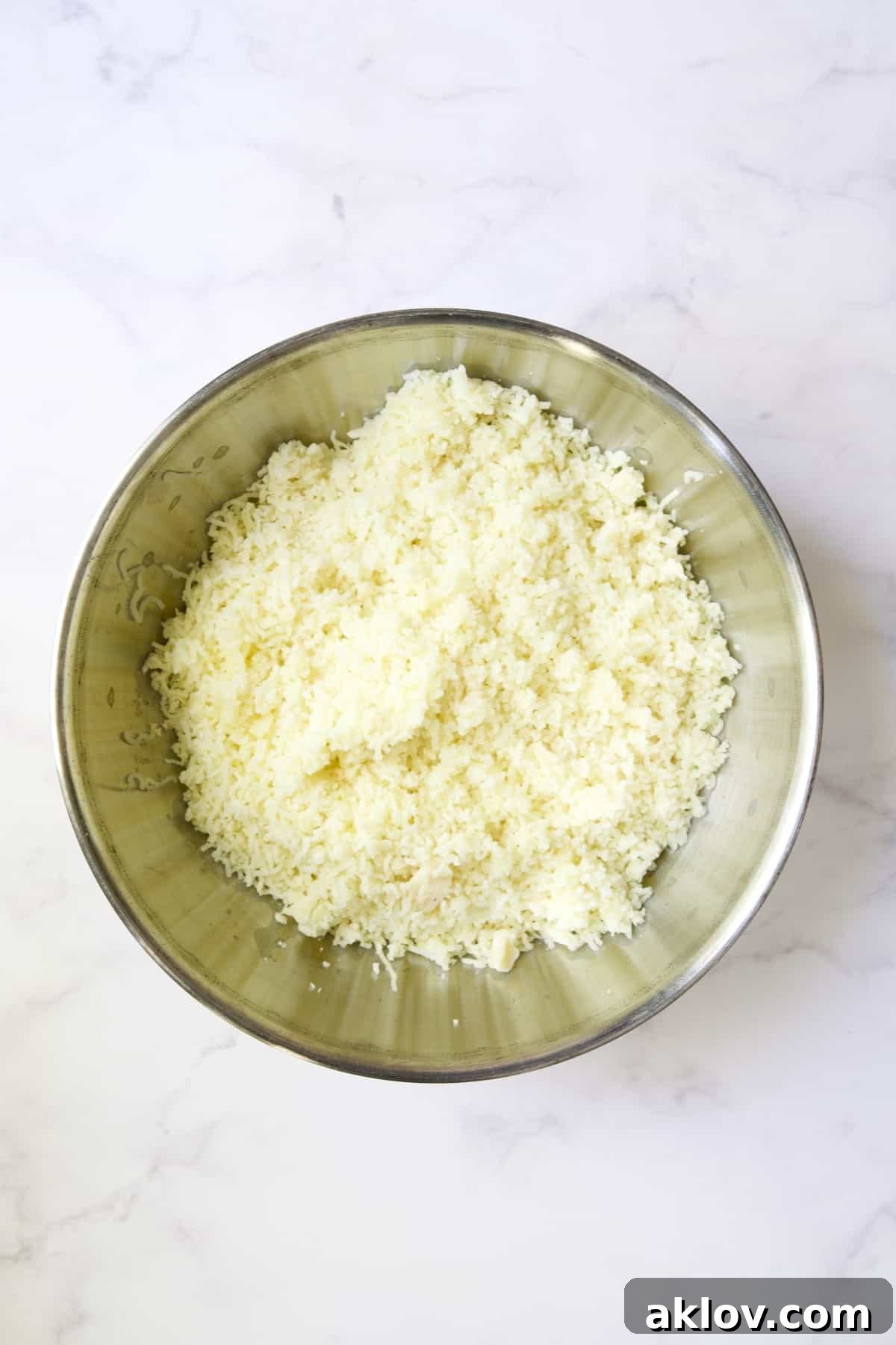 A bowl filled with finely riced potatoes and garlic, perfectly textured and ready for the next steps.