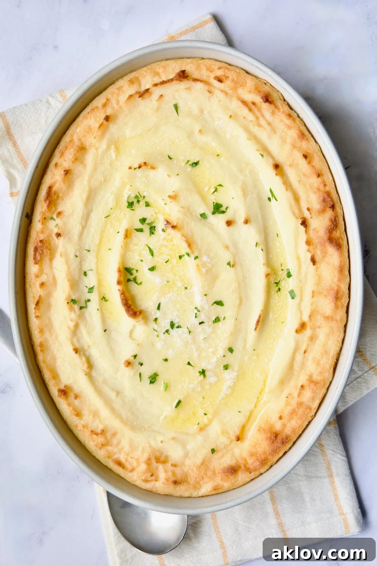 A beautifully baked oval dish of Twice-Baked Mashed Potatoes, featuring a golden-brown, lightly crisp top and creamy interior.
