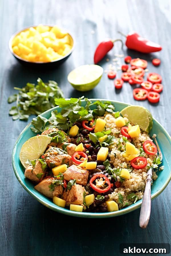 A tastefully arranged Cuban Chicken and Black Bean Quinoa Bowl, with vibrant garnishes delicately placed in the background, highlighting the freshness of the ingredients.