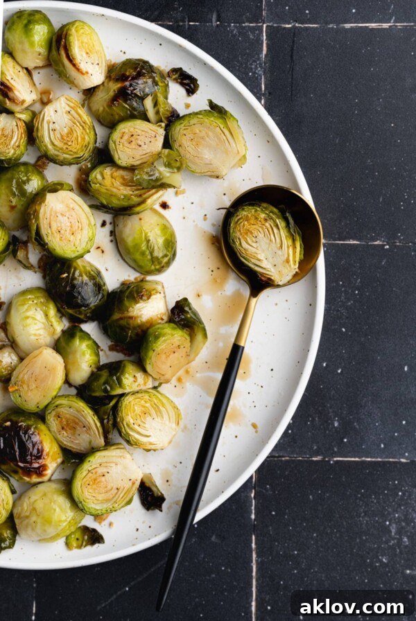 Sweet and Salty Brussels Sprouts, close-up with one sprout on a spoon, showcasing its glossy coating.