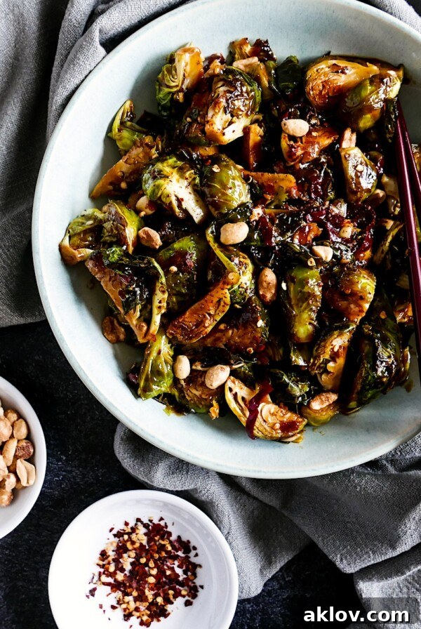 Kung Pao Brussels Sprouts in a round white serving bowl, garnished with peanuts.