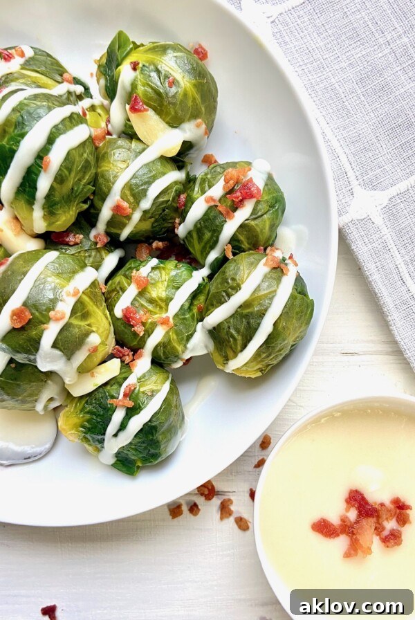 Steamed Brussels sprouts on a white plate with a side of horseradish sauce.