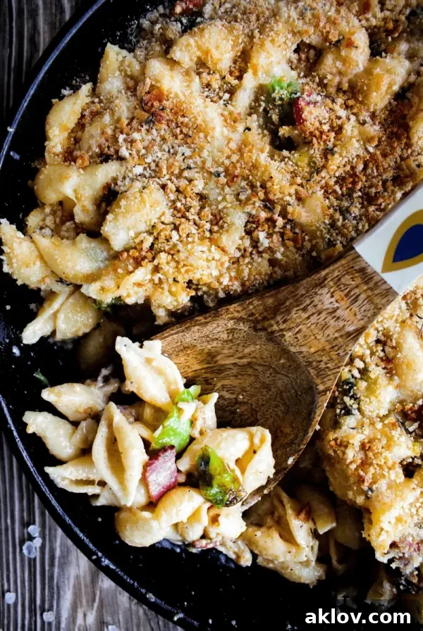Mac and Cheese with Brussels Sprouts and Bacon in a cast iron skillet, bubbling with cheesy goodness.
