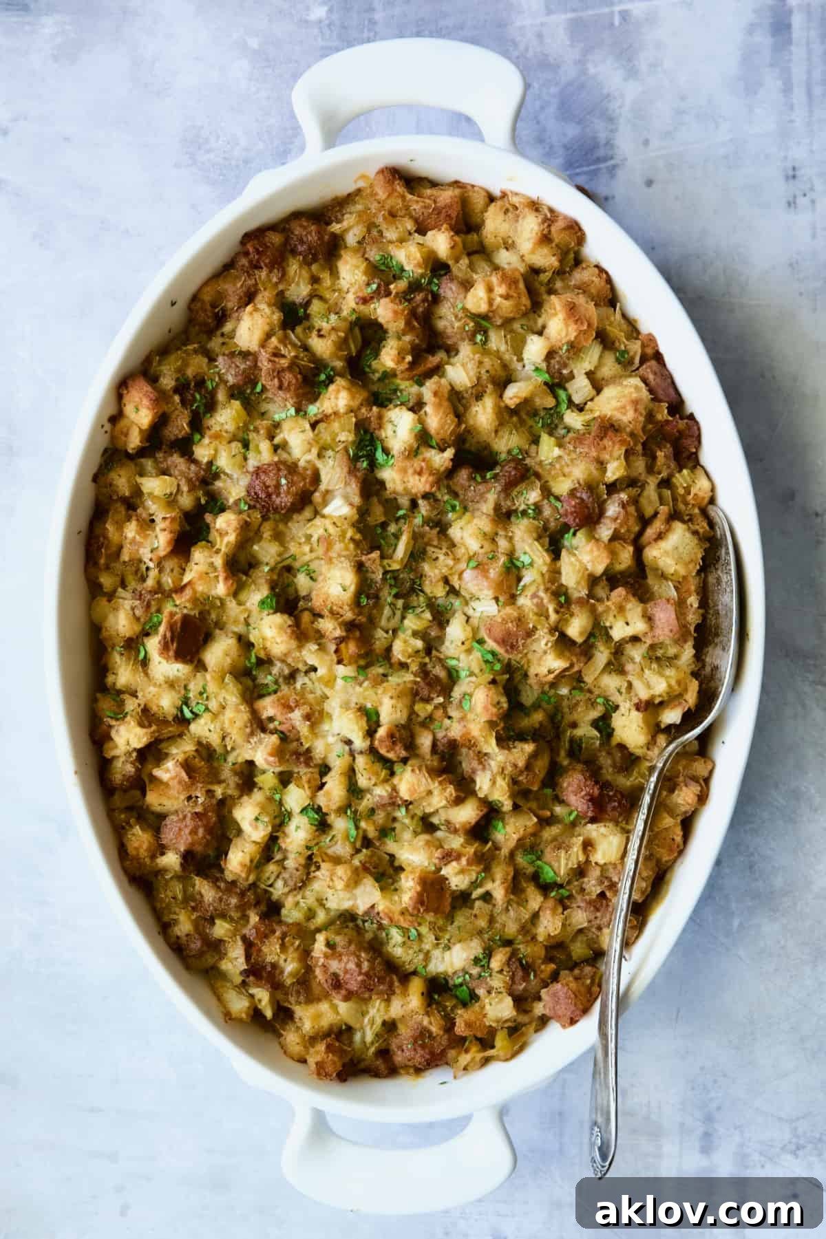 Aromatic Fennel and Leek Sausage Stuffing 13 A close-up of baked Sausage Stuffing with Fennel and Leeks in a white oval gratin dish, showcasing its crispy top and moist interior.