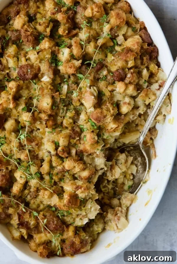 Sausage Stuffing with Fennel and Leeks in white oval gratin dish with serving spoon. A visually appealing holiday side dish.