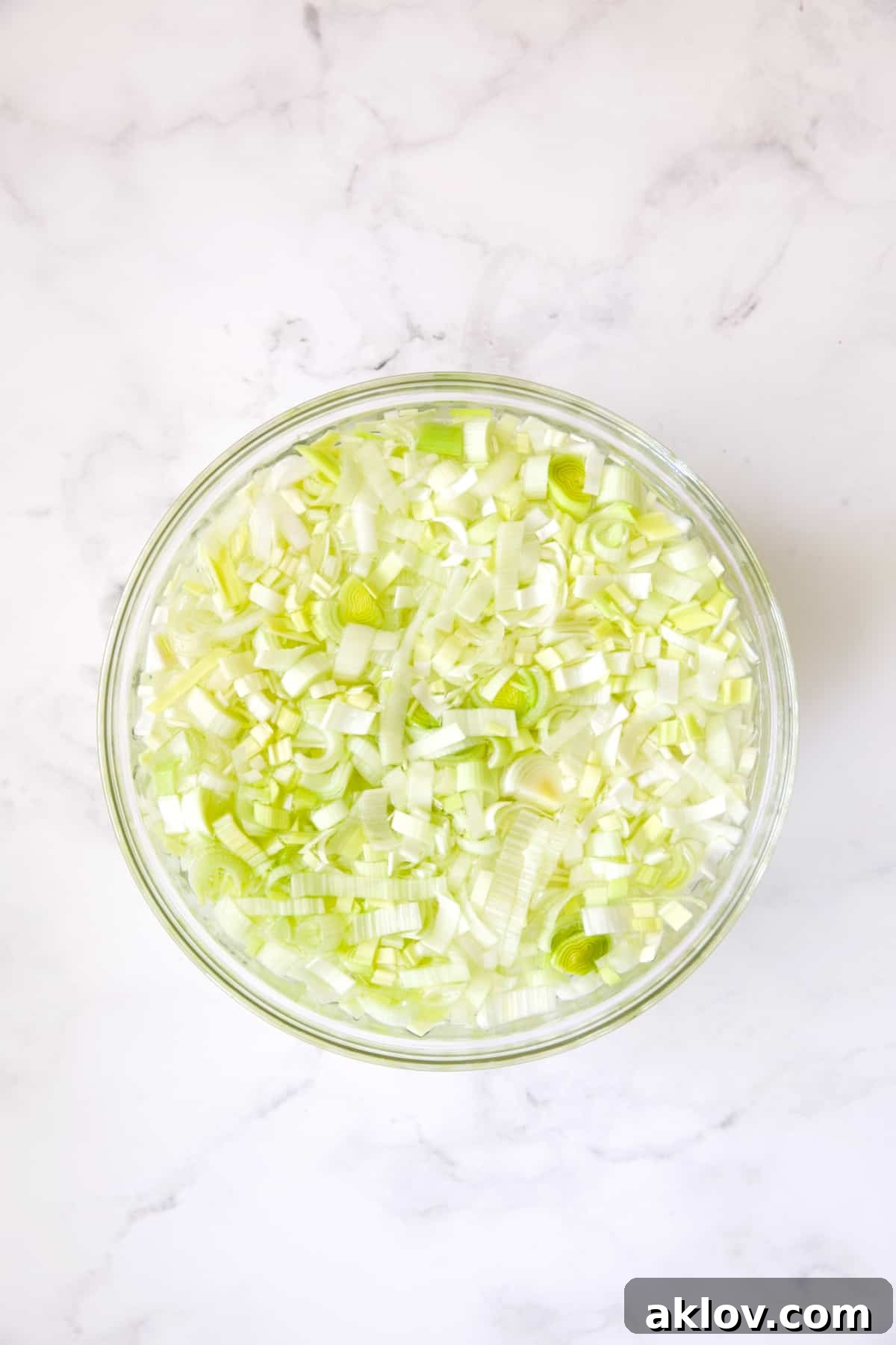 Aromatic Fennel and Leek Sausage Stuffing 5 Sliced leeks soaking in water in a clear glass bowl to remove dirt.