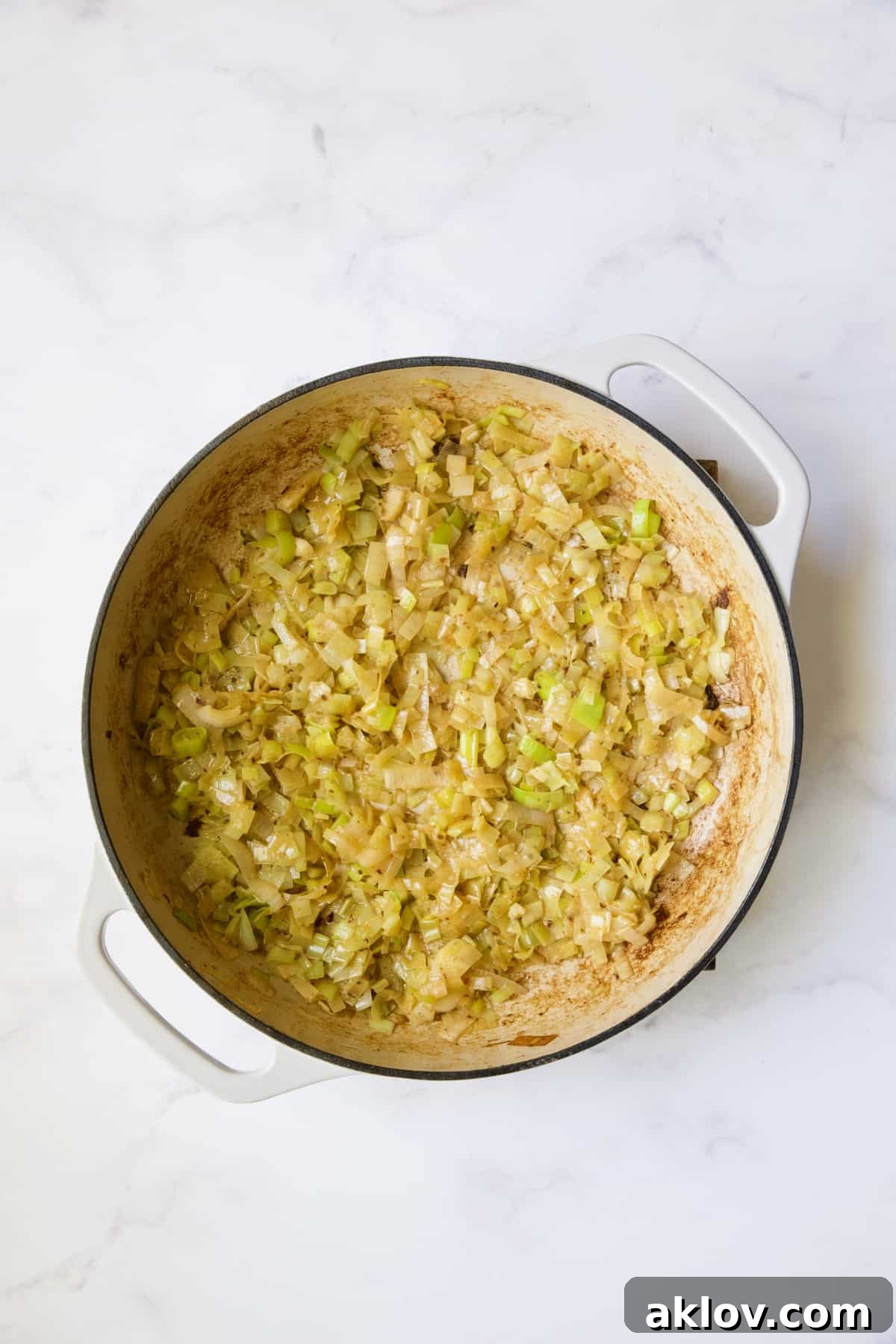 Sautéed leeks, tender and lightly golden, cooked in a white enamel cast iron skillet.
