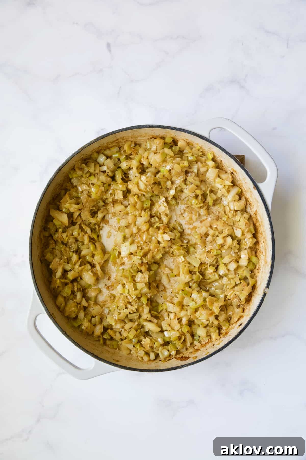 A vibrant mix of cooked fennel, leeks, and celery in a white enamel cast iron skillet, fragrant and tender.