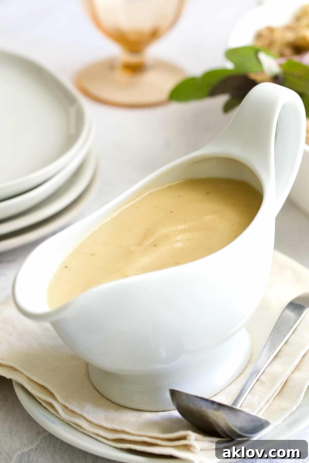 Rich, homemade gravy perfectly served in a elegant white gravy boat on a rustic beige napkin.