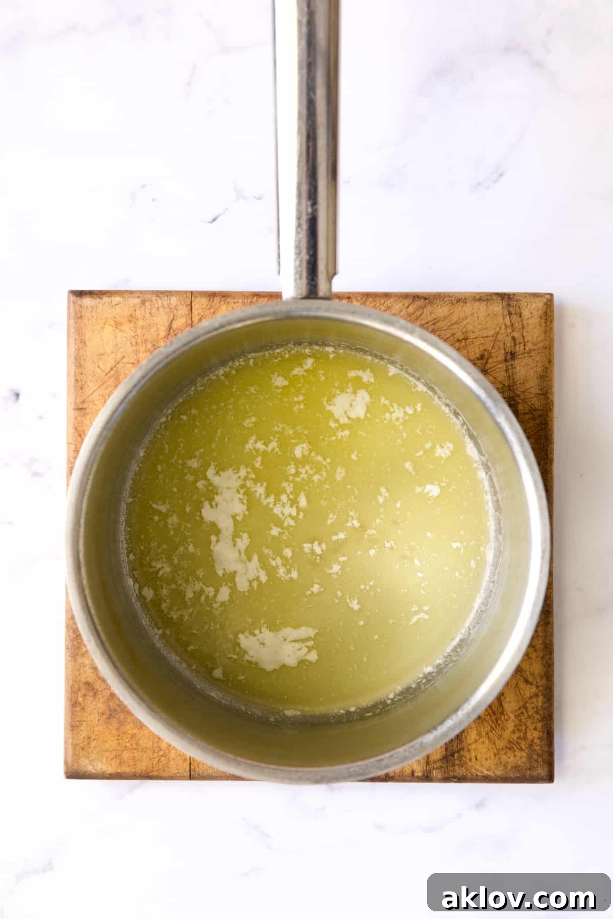 Golden melted butter gleams in the bottom of a stainless steel saucepan, ready for the next step.