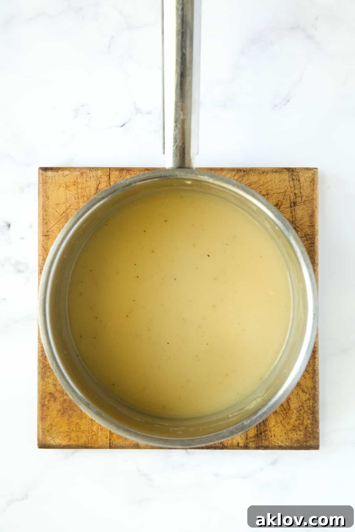 Thick, rich gravy simmering gently in a stainless steel saucepan, showing its perfect consistency.