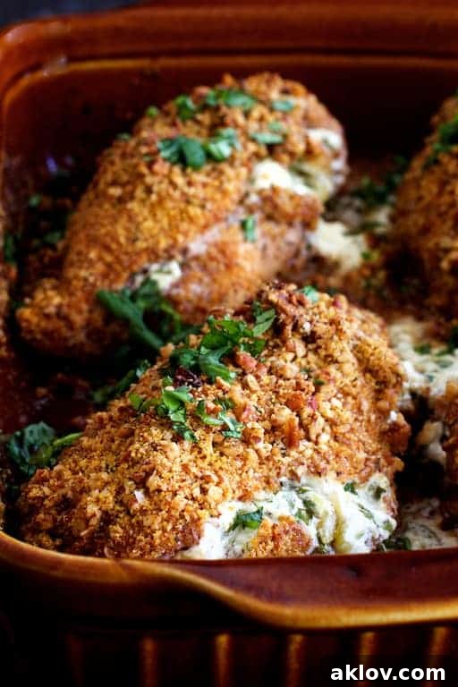 Green Chile Goat Cheese Stuffed Chicken Breasts with Spicy Cornmeal Pecan Crust arranged neatly in a clay baking dish, ready to be served.