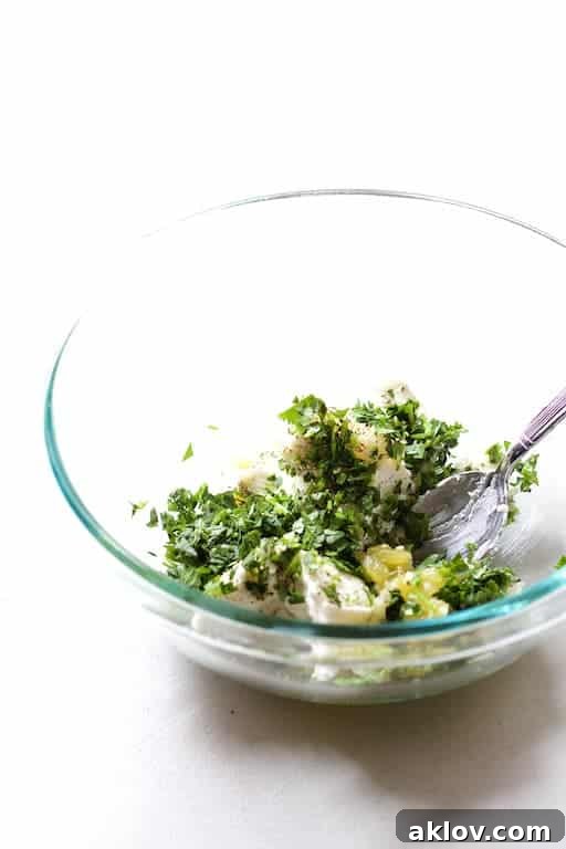Image showing the process of mixing green chile and goat cheese filling in a clear glass bowl, ready for stuffing.