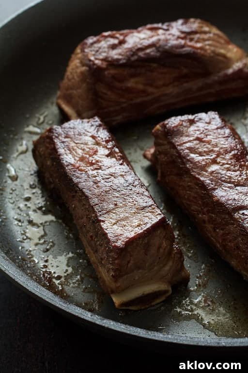Photo of browned beef short ribs on the bone in nonstick skillet.
