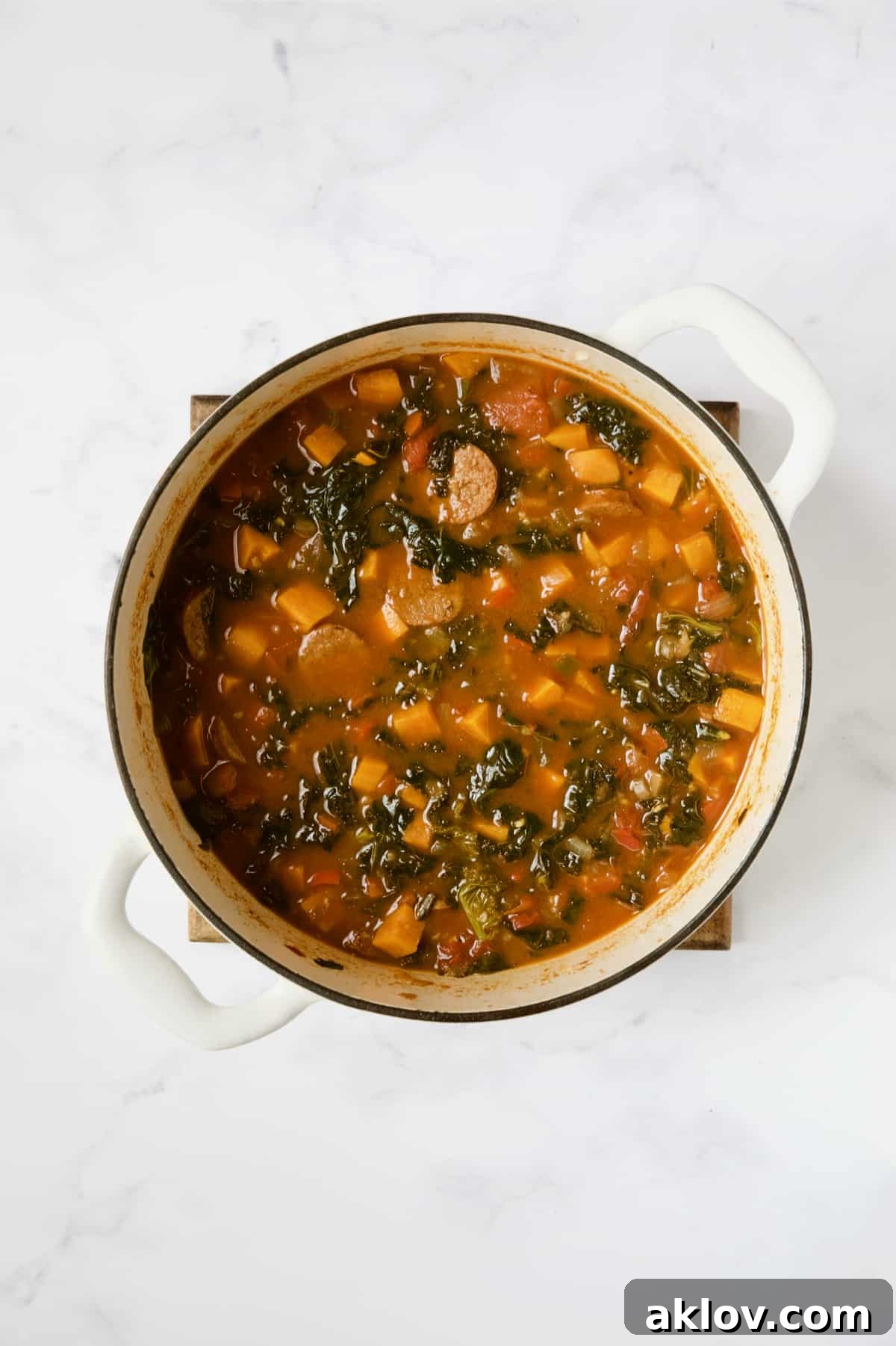 Finished Chorizo Sweet Potato Stew with Kale in white Dutch oven.